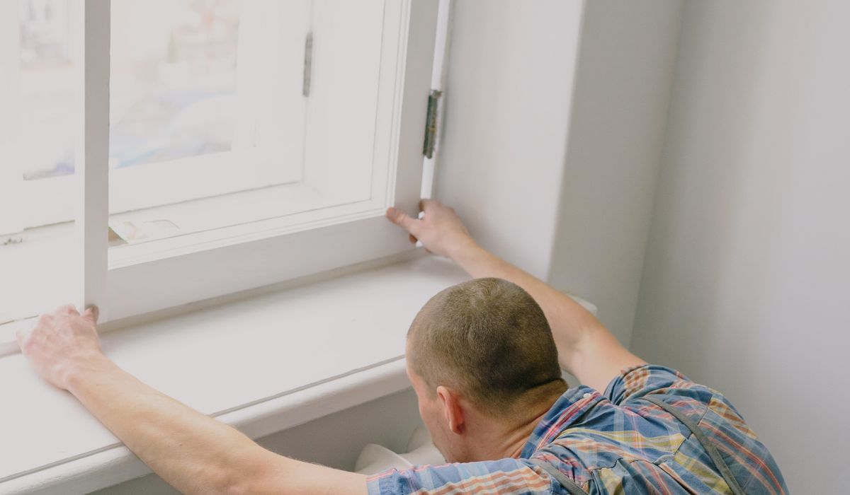 Installer aligning a window sash into its frame from inside the room